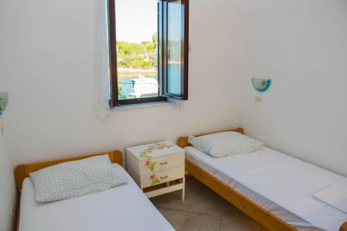 two beds in a room with a window at Apartments Punta Blue & Orange in Punta Križa