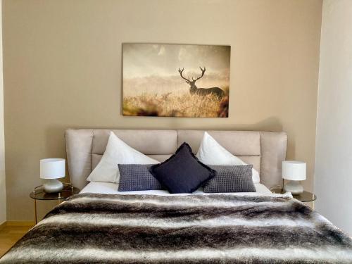 a bedroom with a bed with a deer painting on the wall at STADTVILLA BELLE KITZ im Zentrum mit Sauna by Belle Stay in Kitzbühel
