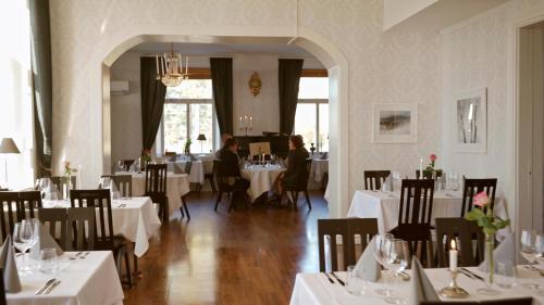 a restaurant with white tables and chairs and people sitting at tables at Björkuddens Hotell & Restaurang in Sandöverken