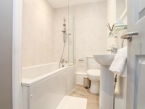 a white bathroom with a toilet and a sink at Lighthouse Lofts - Godrevy in Camborne