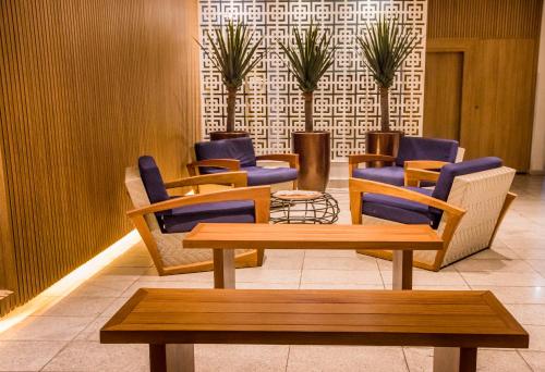 a waiting room with chairs and tables and plants at Hotel Morada do Sol in Caldas Novas