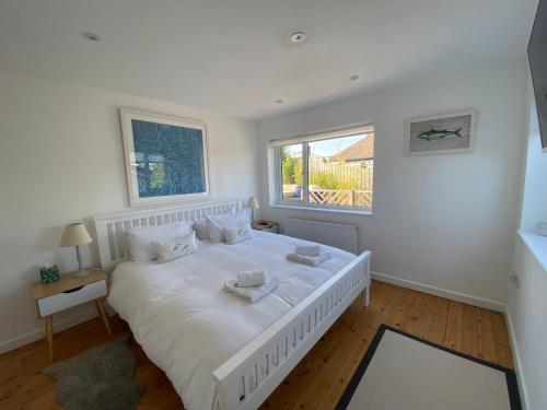 a white bedroom with a large bed and a window at The Bolthole in Kingsbridge