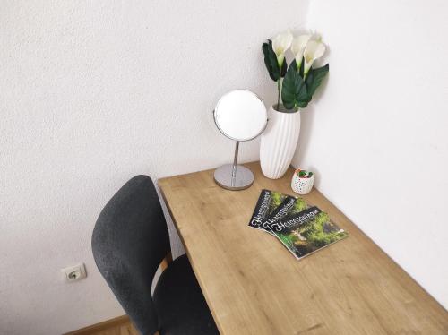 a wooden table with a vase of flowers and a book at Apartment Katica Mostar in Mostar