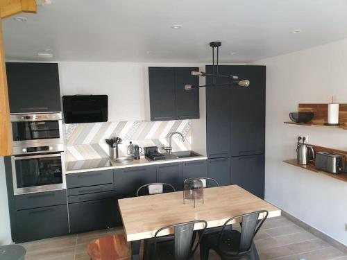 eine Küche mit einem Holztisch und Stühlen darin in der Unterkunft Maisonnette individuelle pour 4 personnes 2 chambres Terrasse - Design & Haute Qualité in Bourbourg