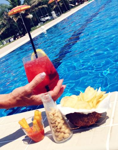 a person holding a drink next to a pool at Residence Nova Marina in Sottomarina