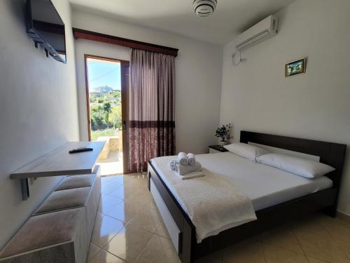 een slaapkamer met een bed, een bureau en een raam bij Guesthouse Redilka in Ksamil