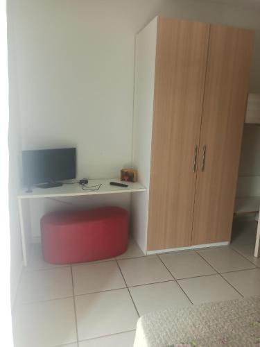 a room with a desk with a monitor and a red stool at Village Aldeia das águas 1° Andar in Nossa Senhora das Dores