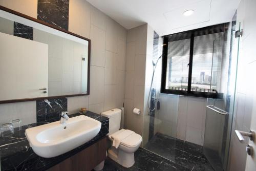 a bathroom with a sink and a toilet and a mirror at The Landmark Penang in Tanjong Tokong