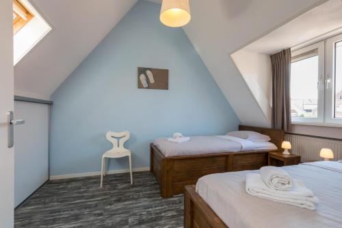 a attic bedroom with two beds and a chair at Holidayhouse - - Zuidstraat 4 Zoutelande in Zoutelande