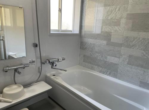 a bathroom with a tub and a toilet and a sink at Holiday Villa 旅生 in Tonosho