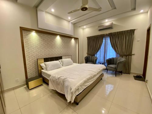 a bedroom with a large bed and two chairs at Luxury Guest House in Bahria Town in Rawalpindi