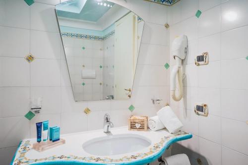 bagno con lavandino e specchio di Hotel Myage a Ischia