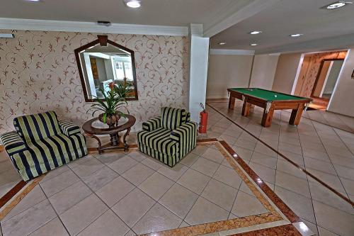 a living room with two chairs and a pool table at Hotel Firenze in Serra Negra