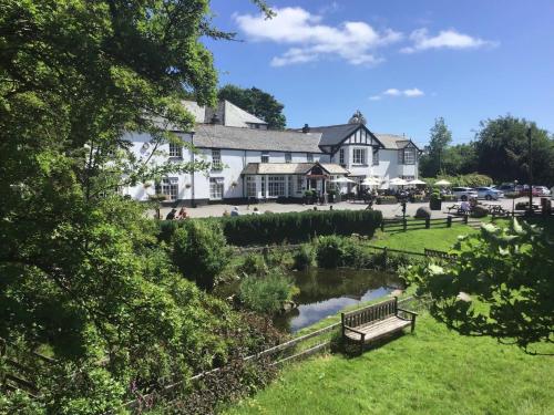 a building with a park with a bench and a pond at Two Bridges Hotel in Two Bridges
