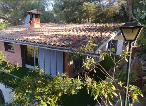 a house with a tiled roof and a street light at Camping Cala Llevado in Tossa de Mar