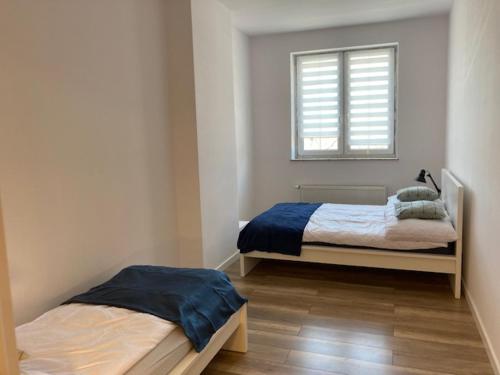 a bedroom with two beds and a window at Apartament Centrum Szczytno II in Szczytno