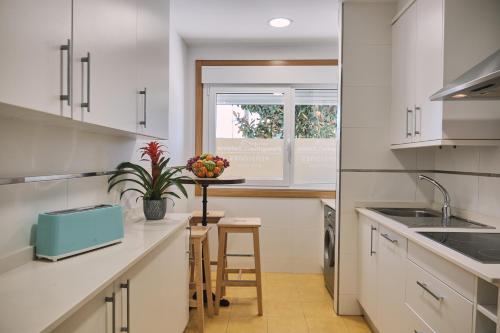 eine Küche mit weißen Schränken, einem Waschbecken und einem Fenster in der Unterkunft Pensión A Solaina 2 in O Pino 