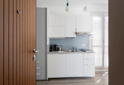 a kitchen with white cabinets and a sink at SkyView Nolo Studio Via Varanini in Milan