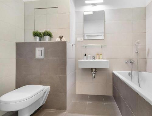 a bathroom with a toilet and a sink and a tub at Sunflower - Modern large charming apartment with balcony in Bratislava