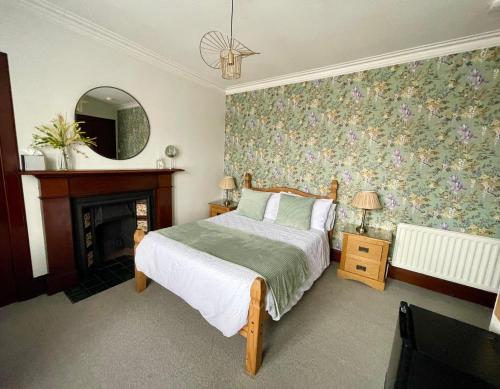 a bedroom with a bed and a fireplace and a mirror at Crown House in Inverness