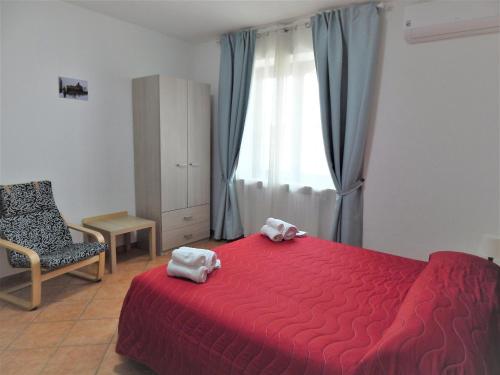 1 dormitorio con cama roja, silla y ventana en Amo' le Langhe, en Narzole