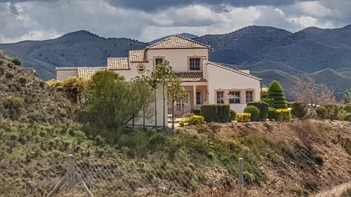 a house on a hill with mountains in the background at Villa Rosada - luxurious 3-bedroom villa with garden and pool in Cantoria