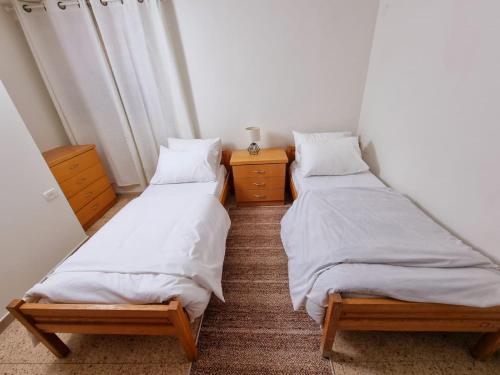 two twin beds in a room with two night stands at הבית בפסוטה in Fassuta
