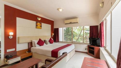 a hotel room with a bed and a television at Presidency Landmark in Daman