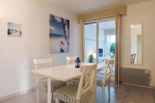 a dining room with a white table and chairs at L'Aigrette - Front de mer-Accès direct plage in Leucate