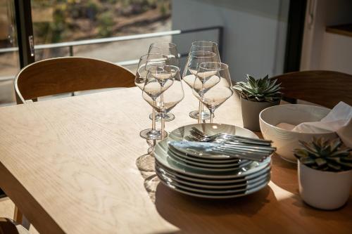 a wooden table with plates and wine glasses on it at Seametry Luxury Living Penthouse in Souda