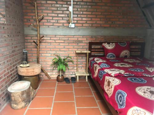 um quarto com uma cama e uma parede de tijolos em Bầu Bí Mini Farmstay Mekong - Tiền Giang em Mỹ Tho