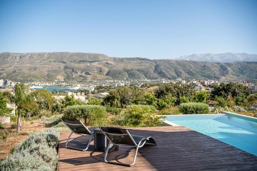 two chairs sitting on a deck next to a swimming pool at Seametry Luxury Living Penthouse in Souda