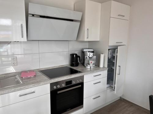 a white kitchen with a sink and a stove top oven at Ostfrieslands Perle Ferienwohnung an der Nordseeküste, Sauna, Terrasse, Garten, ruhige Lage, WLAN in Norden
