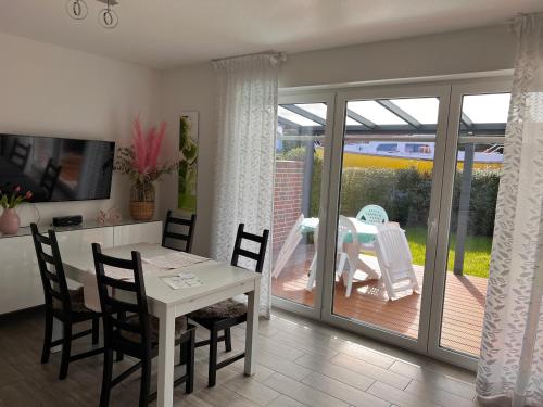 a dining room with a table and chairs and a patio at Ostfrieslands Perle Ferienwohnung an der Nordseeküste, Sauna, Terrasse, Garten, ruhige Lage, WLAN in Norden