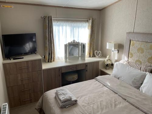 um quarto com uma cama, uma televisão e uma janela em Beautiful 2 bedroom Helmsley Lodge em Northampton
