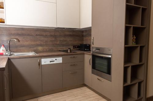 een keuken met witte kasten en een wastafel bij Апартамент ФЕЯ - топ център, безплатно паркомясто in Gabrovo