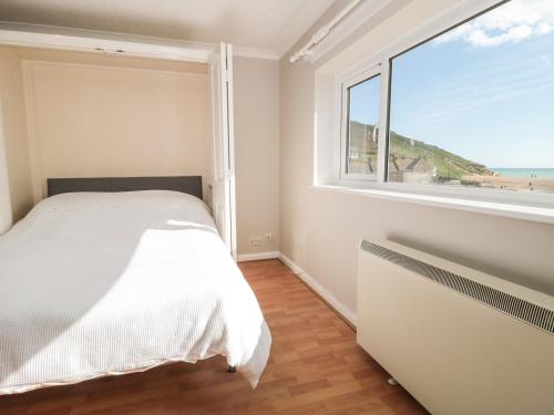 a bedroom with a bed and a large window at Flat 30 in West Bay