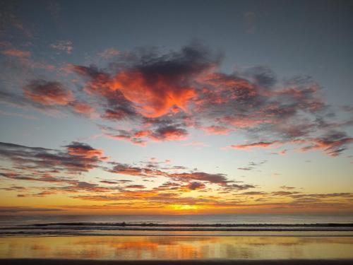 a sunset on a beach with the ocean at Palm Beach Inn in Playa Grande