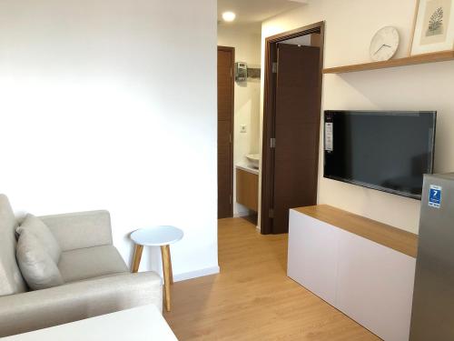 ein Wohnzimmer mit einem Sofa und einem Flachbild-TV in der Unterkunft Zen Inspired 2-bedroom Apartment with Mountain City View in Bandung
