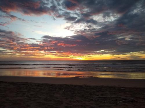 a sunset on a beach with the ocean at Palm Beach Inn in Playa Grande