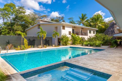 a swimming pool in front of a house at Palm Beach Inn in Playa Grande