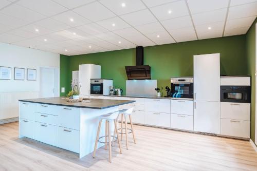 a kitchen with white cabinets and a green wall at XXL Ferienhaus Goldberger See - Sauna - 16 Personen in Goldberg