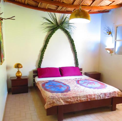 a bedroom with a bed with a palm tree above it at KASA HIBISCUS in Kafountine