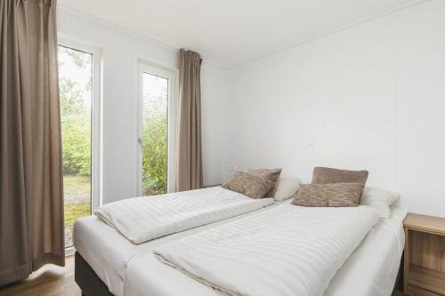 uma grande cama branca num quarto com uma janela em Forest lodge with hot tub - 4 people em Rijssen