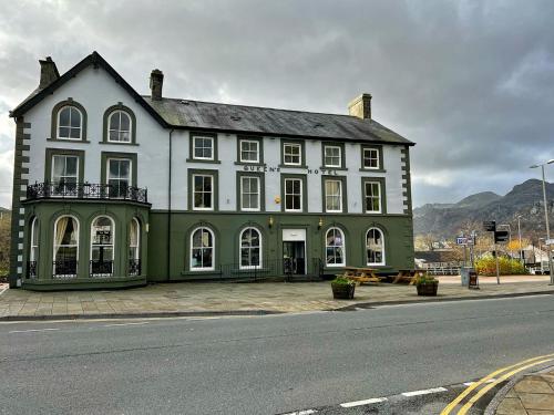 un grande edificio verde e bianco sul lato di una strada di Queens Hotel a Blaenau Ffestiniog