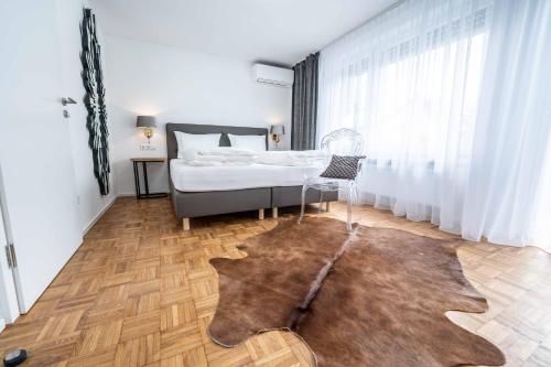1 dormitorio con cama y alfombra en City Apartments FN L 6 KLIMATISIERT mit Balkon - Deluxe Doppelzimmer, en Friedrichshafen