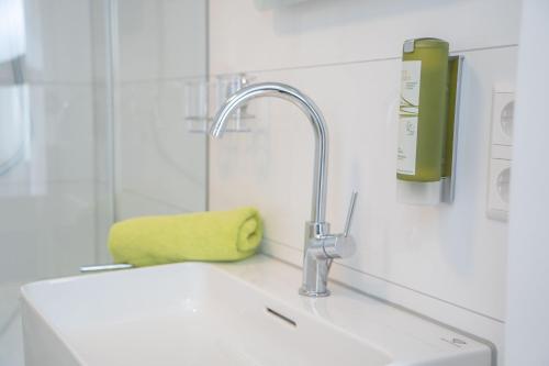 eine Küchenspüle mit Wasserhahn und einem grünen Schwamm in der Unterkunft City Apartments FN L 6 KLIMATISIERT mit Balkon - Deluxe Doppelzimmer in Friedrichshafen