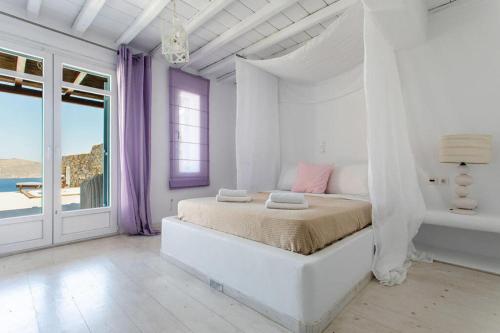 a white bedroom with a bed and a view of the ocean at Villa ANASA private Pool & Jacuzzi 8pax at Panormos in Mykonos