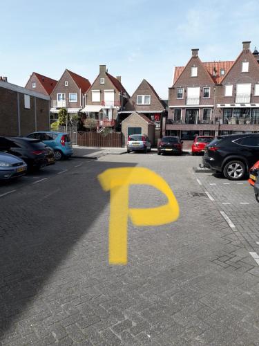 a yellow parking symbol in a parking lot with houses at B&B CaSandra in Volendam