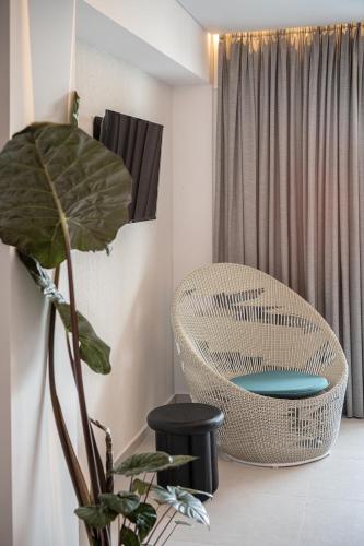 a room with a rattan chair and a plant at Nuovo Luxury Suites in Daratso